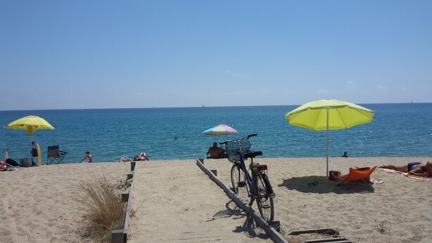 Une plage avec des parasols, un vélo et des gens qui se détendent.