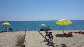 En strand med parasoller, en cykel og folk, der slapper af.