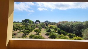 Un balcon donnant sur un jardin aménagé et des arbres.