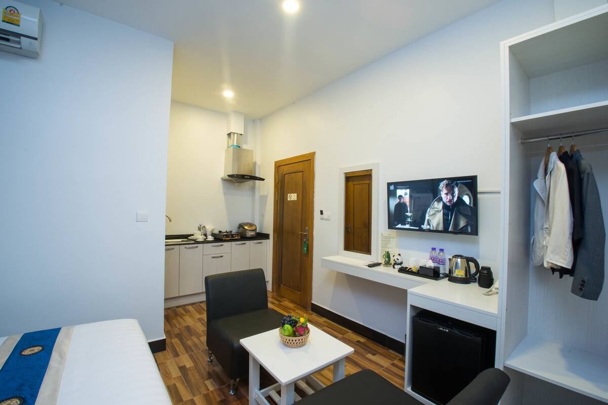 Habitación de hotel compacta con kitchenette, zona de comedor, televisión y armario.