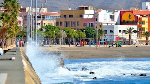 A coastal promenade with a seawall, palm trees, and colorful buildings in the background. - Apartment with terrace, sea views, and satellite TV via Wi-Fi 600 MB (Gran Tarajal)