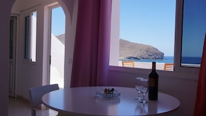 A dining area with a table, chairs, a wine bottle, and a glass. - Apartment with terrace, sea views, and satellite TV via Wi-Fi 600 MB (Gran Tarajal)