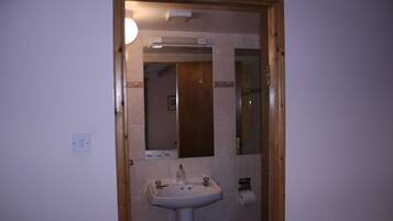 A bathroom with a sink, mirror, and toilet paper holder.