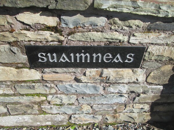 Un mur de pierres sur lequel est apposée une pancarte indiquant « Suisness ».
