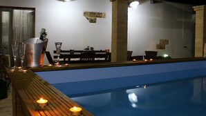 Ett poolområde med ett trädäck, ett bord med stolar och ljus.