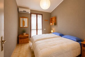 Ein Schlafzimmer mit Bett, Nachttisch, Ablagefläche an der Wand, Spiegel und einem Blumentopf.