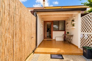 Ein Wohnhaus mit Holzzaun, gefliestem Patio, Essbereich mit Tisch und Stühlen sowie einem weißen Gitterzaun.