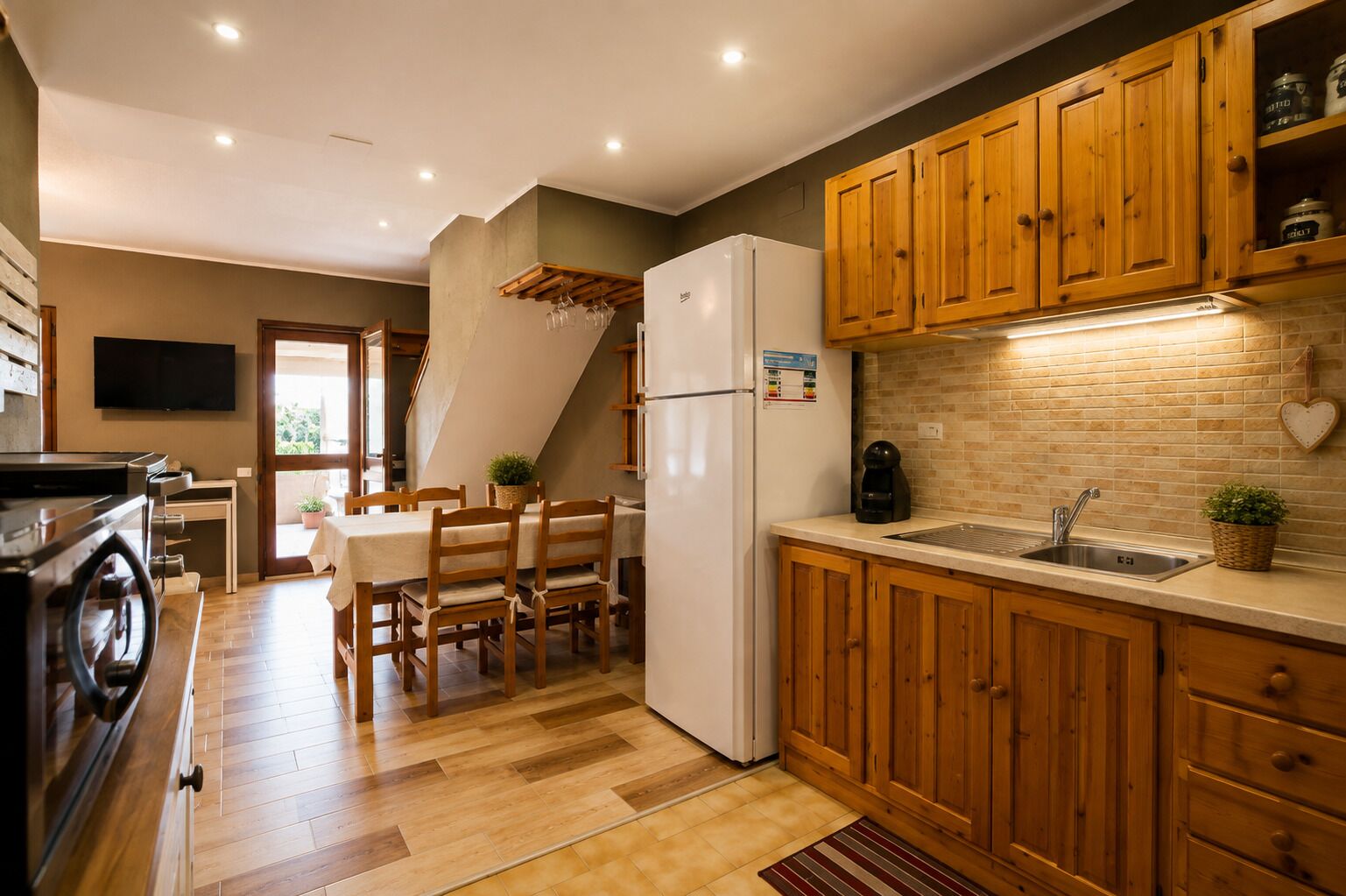 A compact kitchen with wooden cabinets, a built-in oven, and a dining area with a table and chairs.