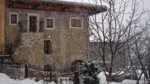A stone building with multiple windows and a snow-covered roof.