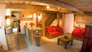 A rustic interior with a kitchen, wooden furniture, and a staircase.