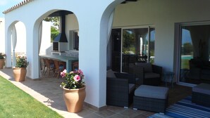 Un espace extérieur abrité avec une terrasse, des sièges et un barbecue.