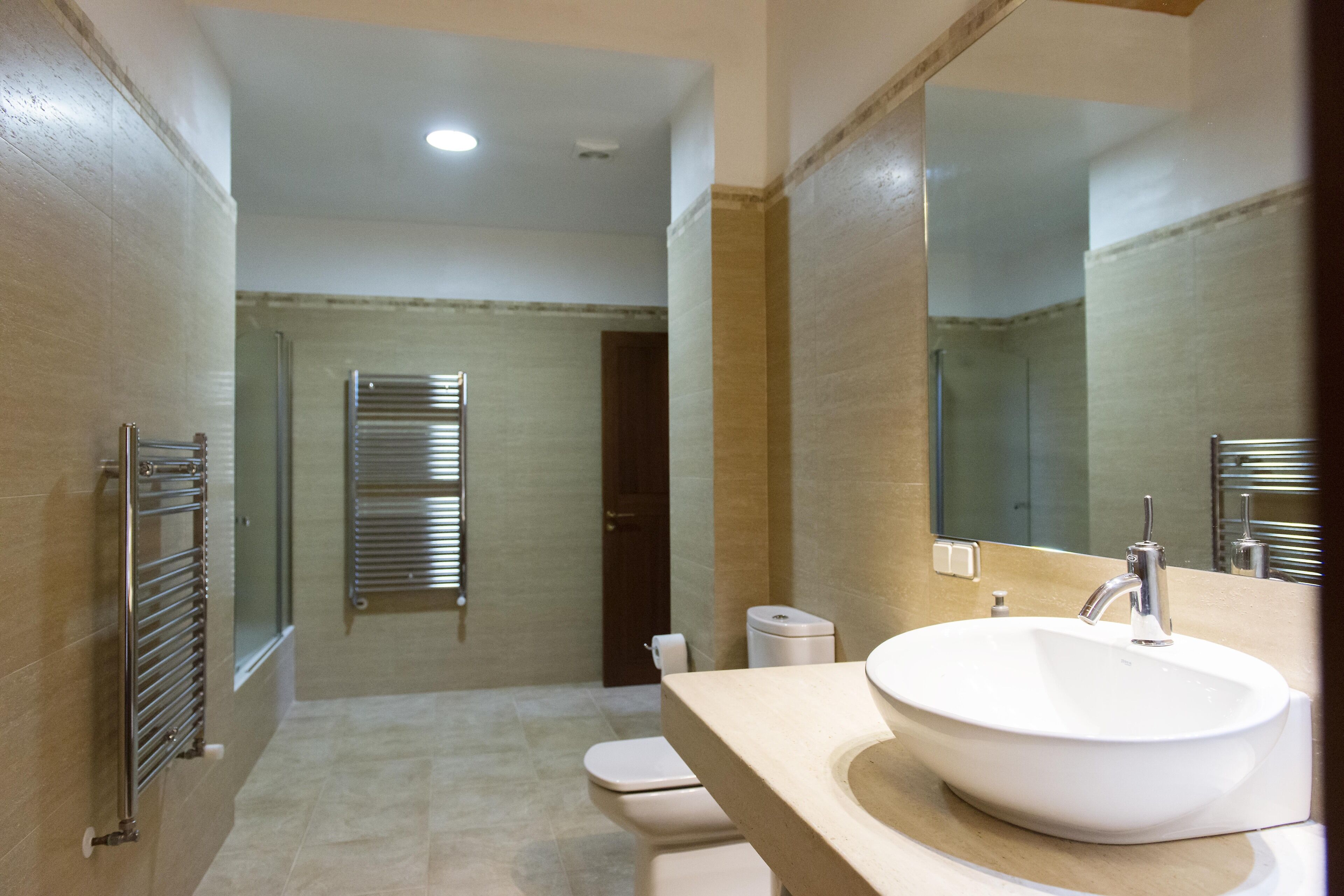 A modern bathroom with a large sink, a mirror, and a towel rack.