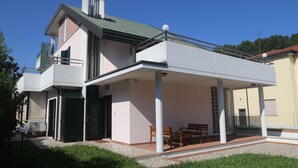 Uma casa moderna de dois andares com um alpendre coberto e um pequeno jardim.