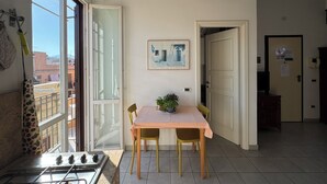 A kitchen with a gas stove, a dining table with chairs, a hanging pendant light, and a view through a glass door. - Historic center, 2 rooms, 2 toilets, sky terrace, lift, free high speed Wi Fi (PALERMO)