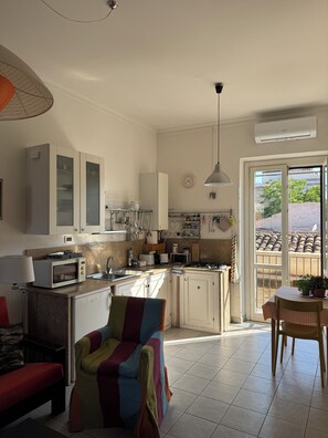 A modern kitchen with white cabinets, a microwave, and a dining area with a table and chairs. - Historic center, 2 rooms, 2 toilets, sky terrace, lift, free high speed Wi Fi (PALERMO)