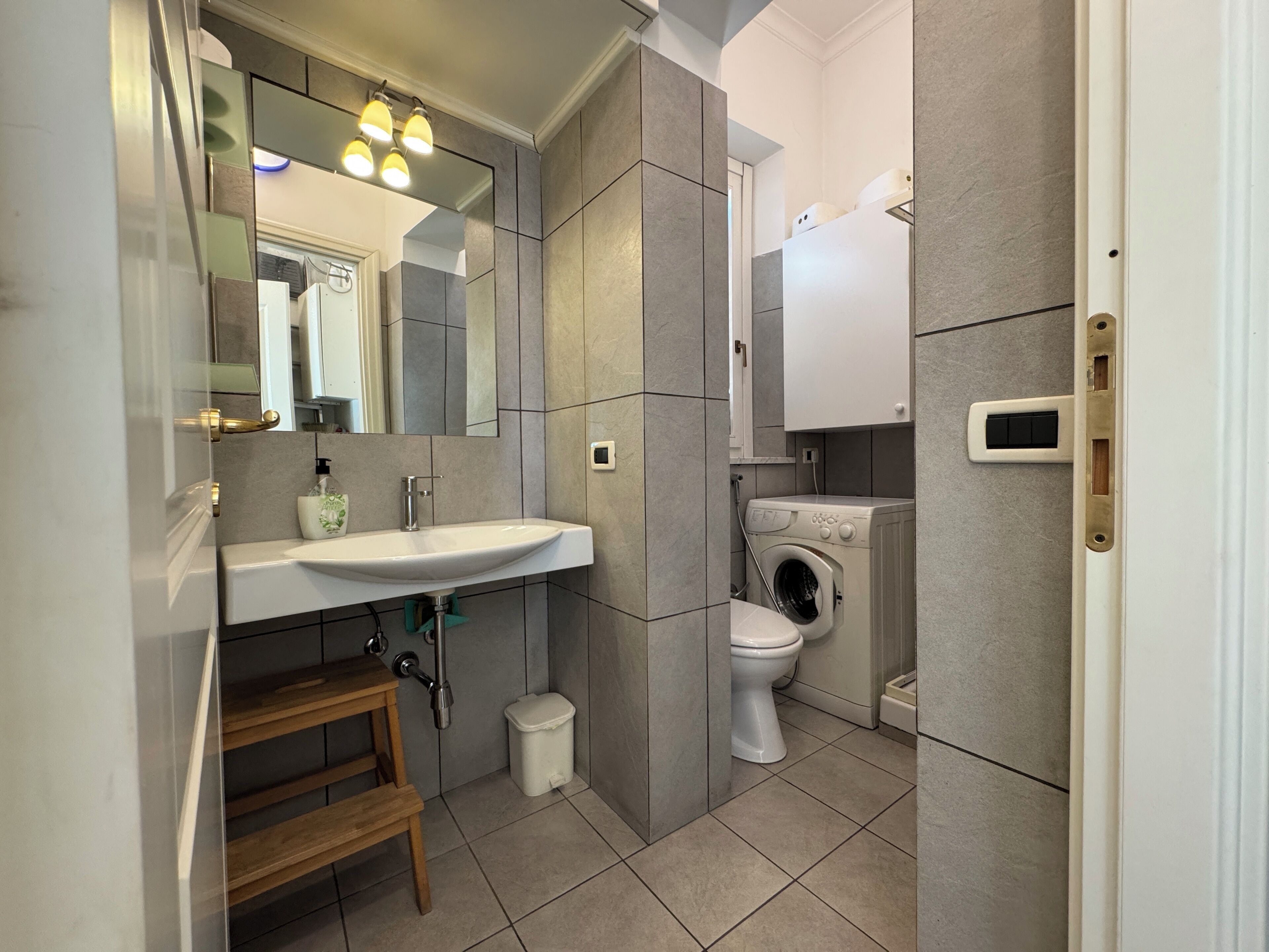 Un bagno moderno con lavandino, specchio e lavatrice.