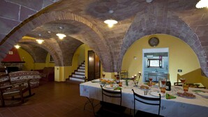 A dining area with a stone vaulted ceiling, a kitchen in the background, and a table set for a meal.