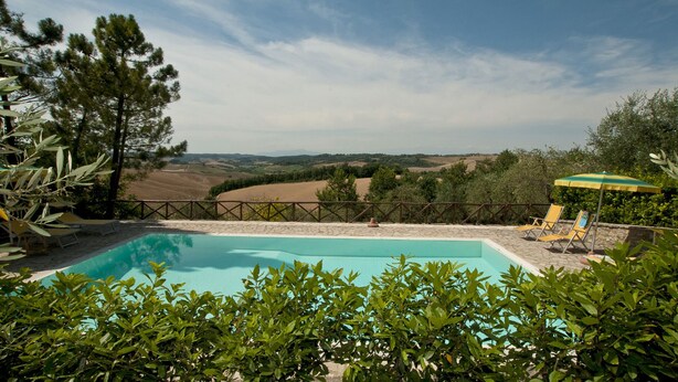 A swimming pool with a view of rolling hills and a wooden fence.