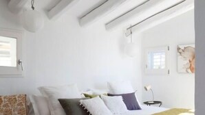 Un dormitorio con una cama, una silla, una ventana y un cuadro en la pared.