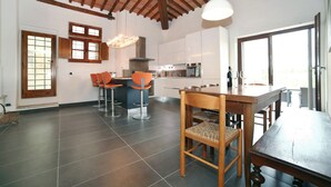 Uma cozinha espaçosa com teto alto, eletrodomésticos modernos e área de jantar com mobiliário de madeira.