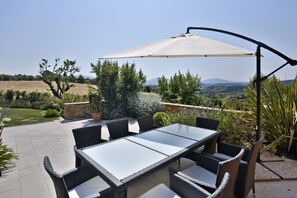 An outdoor patio with a table and chairs, surrounded by greenery and a view of distant hills. - Luxury Villa in the Florentine hills (Florence)