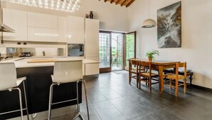 Uma cozinha moderna com armários brancos, uma ilha central e uma área de jantar com cadeiras e mesa de madeira.