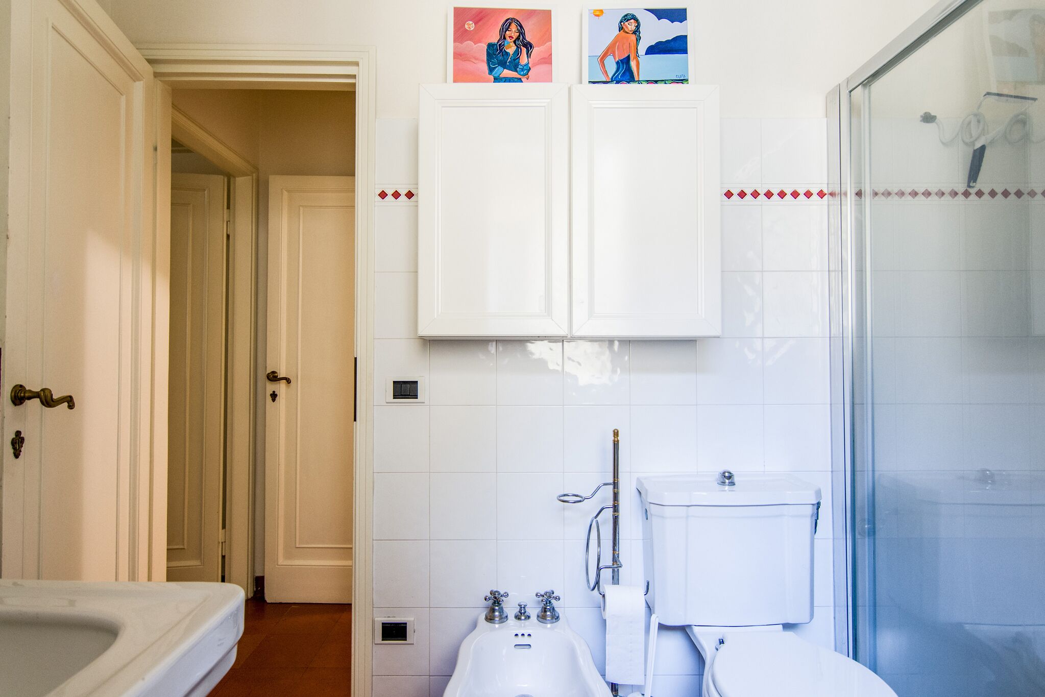 A bathroom with a bathtub, a toilet, and a shower. There are two doors leading to other rooms.
