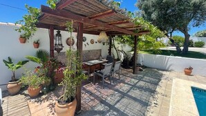 A patio with a pergola, outdoor table and chairs, potted plants, and a swimming pool. - Villa Gabriella 4 bed Villa opposite Golf Course,  3km from the beach (Chiclana de la Frontera)