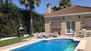 A rectangular swimming pool with clear blue water, surrounded by a tiled deck. There are lounge chairs and a barbecue grill in the background. - Villa Gabriella 4 bed Villa opposite Golf Course,  3km from the beach (Chiclana de la Frontera)