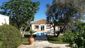 A house with a tiled roof, a swimming pool, and a paved pathway leading to the entrance. - Villa Gabriella 4 bed Villa opposite Golf Course,  3km from the beach (Chiclana de la Frontera)