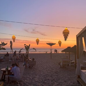 A beachside setting with outdoor seating and hanging lanterns.
