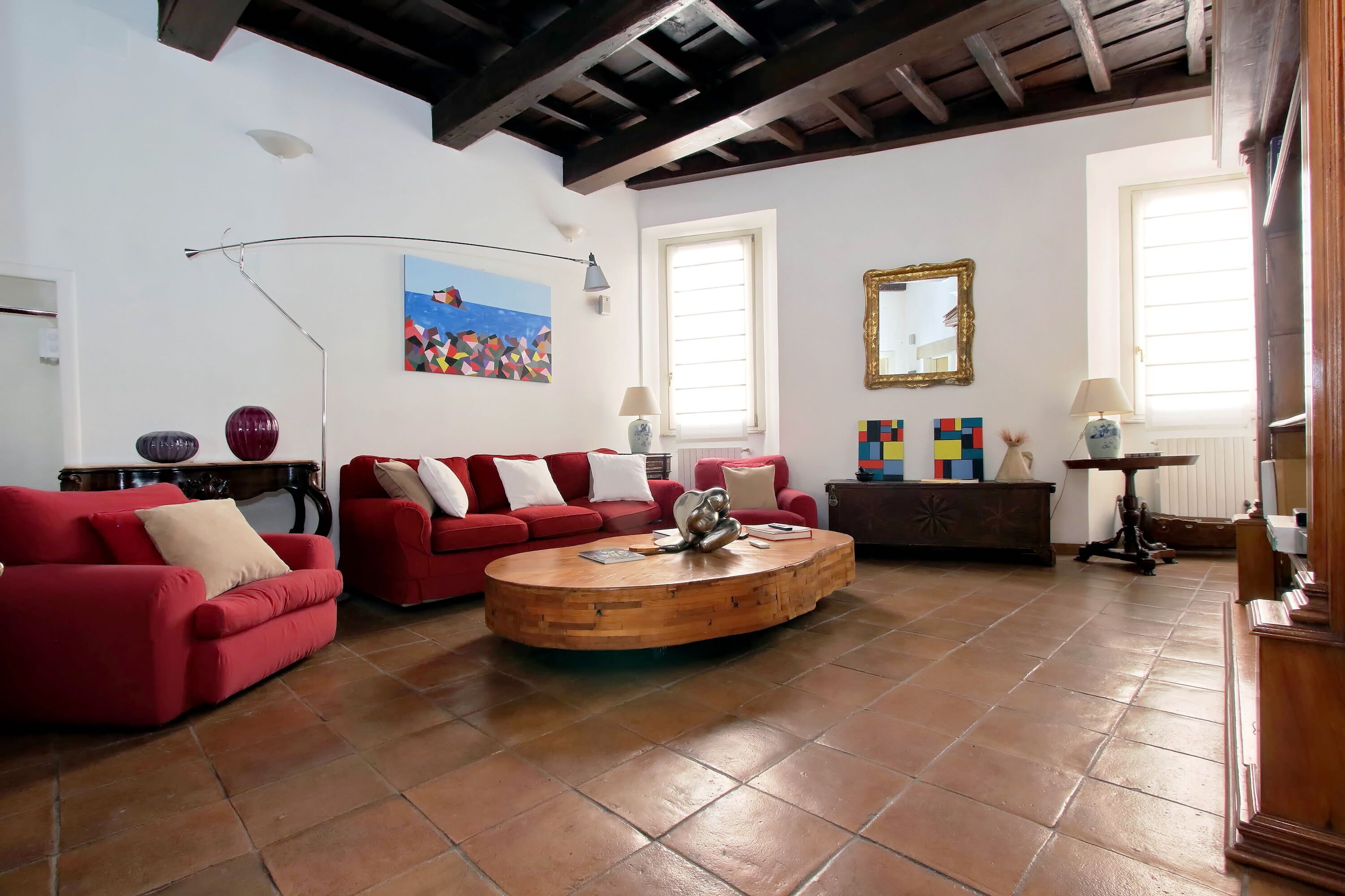 Uma sala de estar com sofás vermelhos, uma mesa de centro de madeira e uma janela grande.