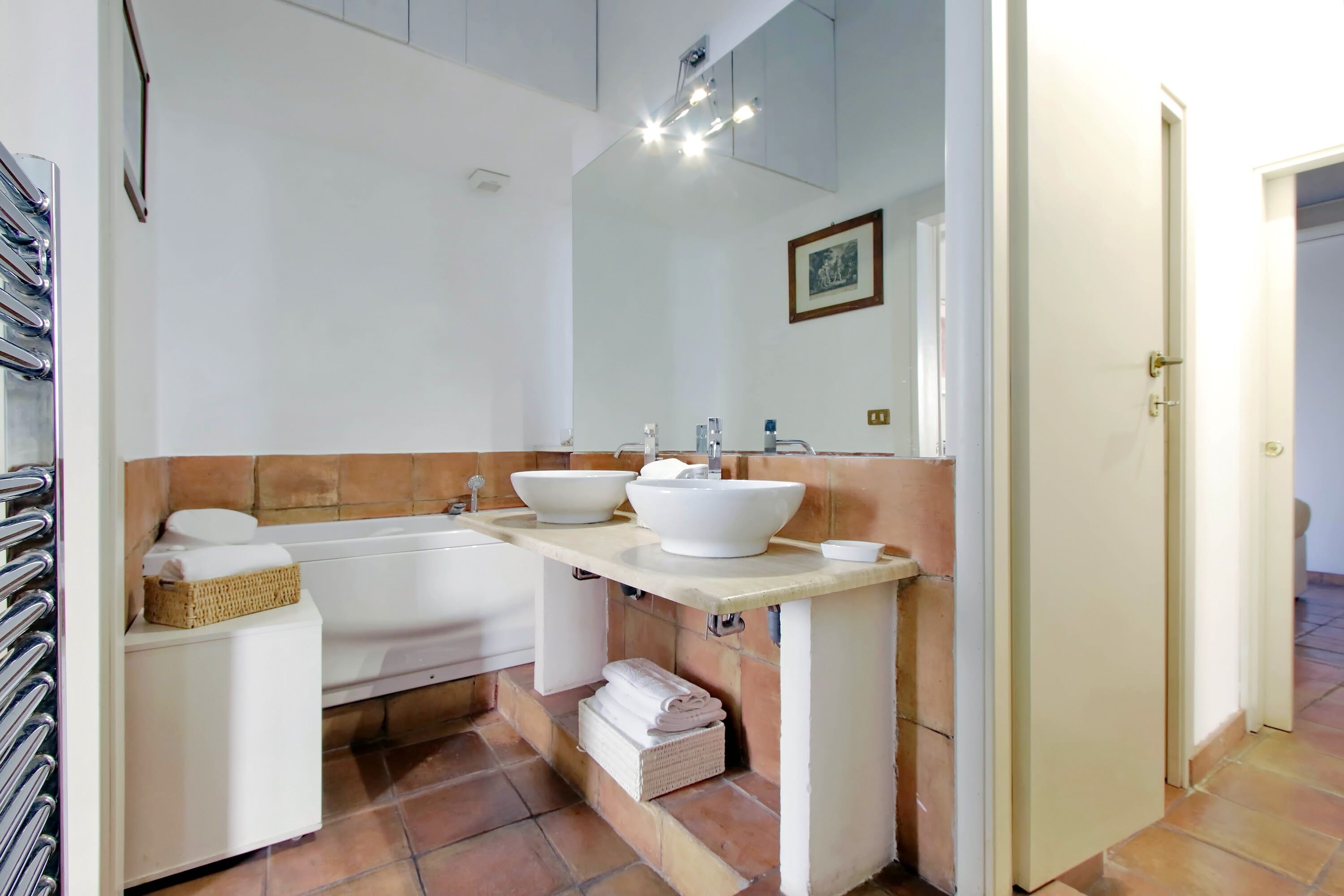 A bathroom with a bathtub, two sinks, and a large mirror.