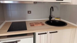 A kitchen with a black sink, a built-in stove, and white cabinets. - Studio - Nevache (Névache)