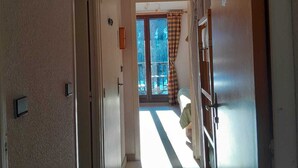 A hallway with a door leading to a room with a bed and a view of a balcony. - Studio - Nevache (Névache)