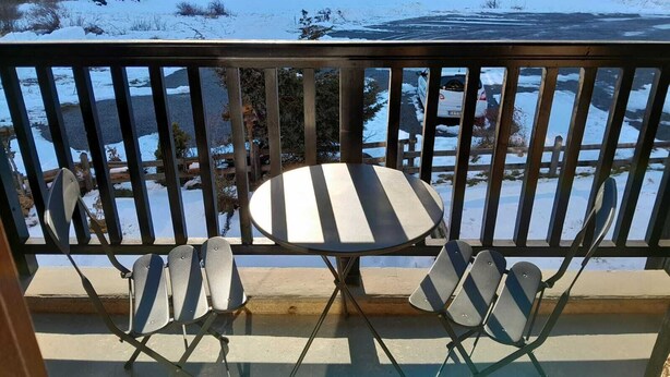A balcony with a table and four chairs, overlooking a snowy landscape with a river and trees. - Studio - Nevache (Névache)
