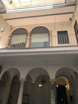 A building with a balcony, arched windows, and a ceiling with a skylight.