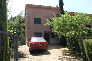 Un immeuble de deux étages devant lequel est garée une voiture rouge.