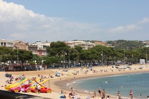 A beach with a sandy shore, a clear sky, and buildings in the background.