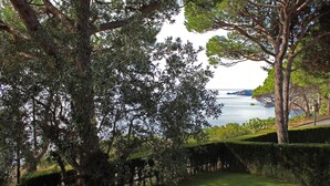 Un jardin aménagé offrant une vue sur un plan d’eau et sur des collines lointaines.