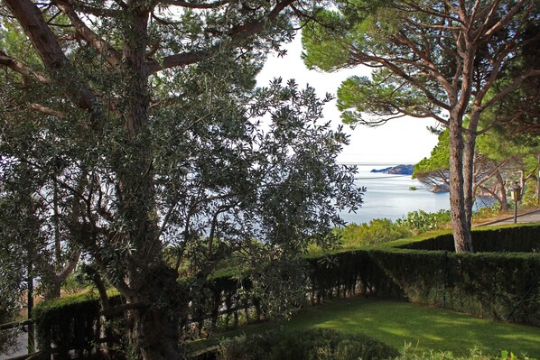 A landscaped garden with a view of a body of water and distant hills.