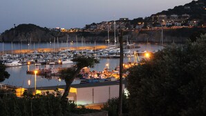 Un port de plaisance où sont amarrés des bateaux, entouré de collines et de bâtiments.