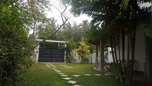 A well-maintained garden with a paved pathway leading to a gated entrance. - Villa Happy Home (Bentota)