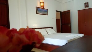 A hotel room with a bed, a nightstand, a wooden wardrobe, and a framed picture on the wall. - Villa Happy Home (Bentota)