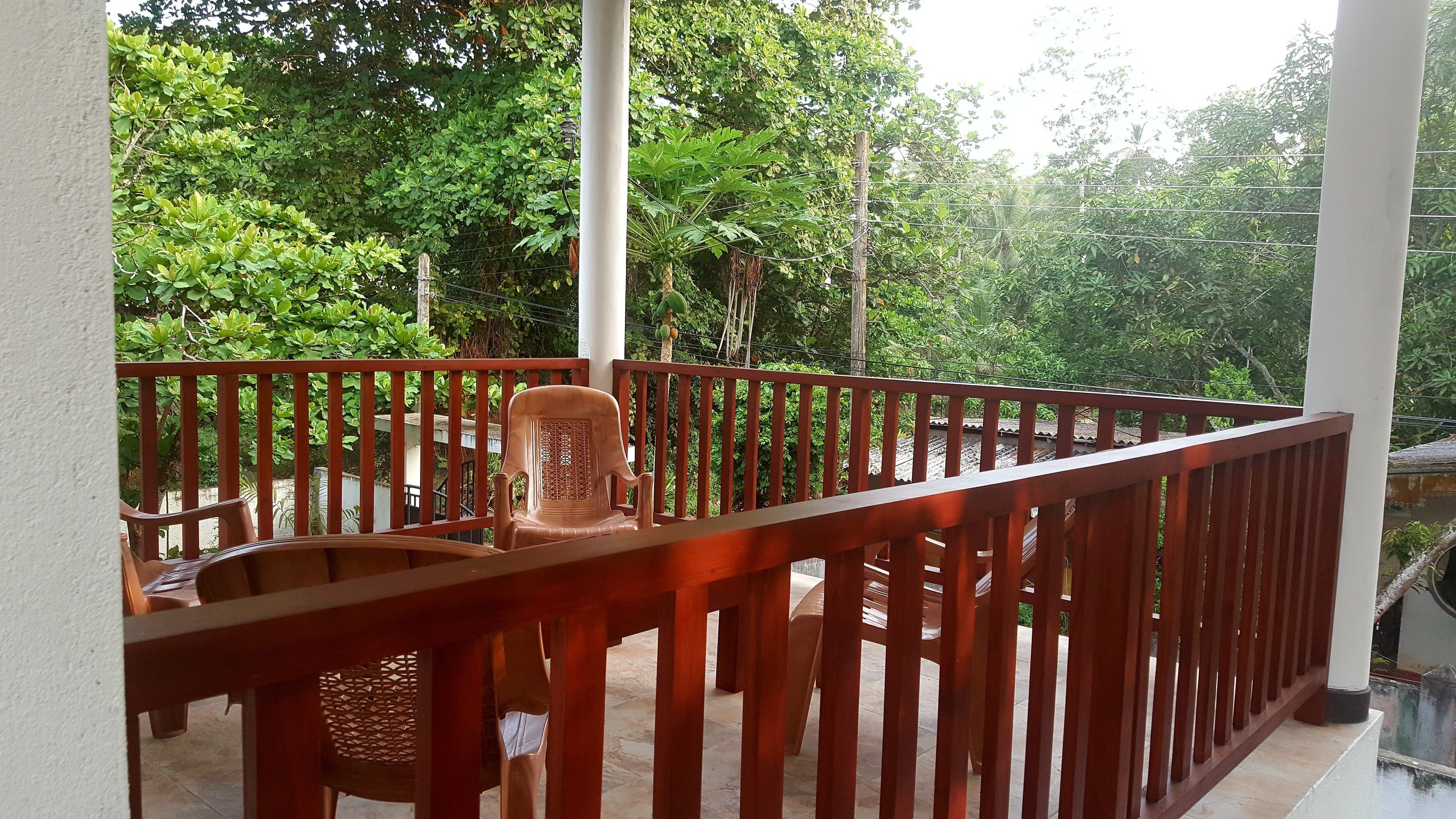 Een houten balkon met uitzicht op weelderige begroeiing.