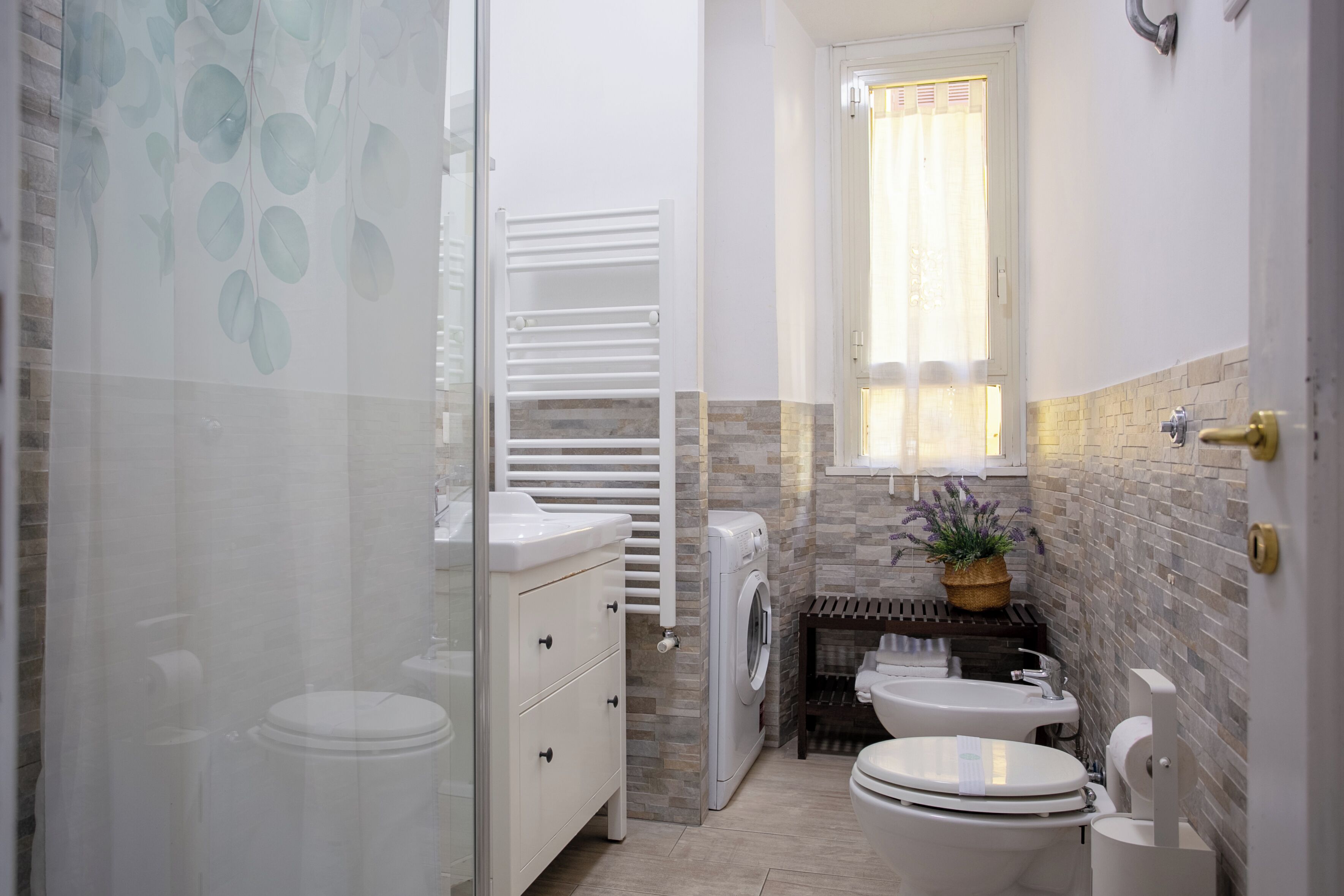 Ein Badezimmer mit Dusche, Toilette, Waschbecken und einem kleinen Fenster.