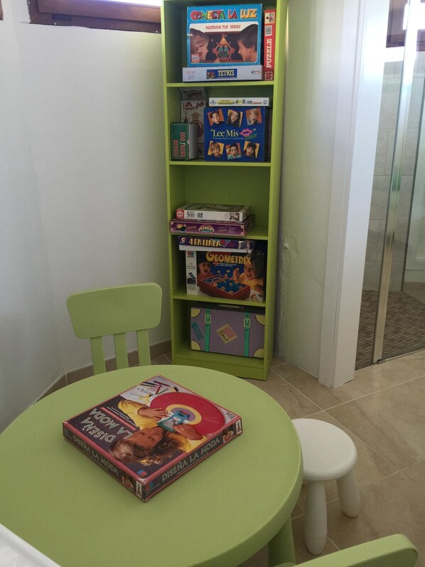 A children's play area with a green table and chair, surrounded by shelves with various educational toys and games. - Villa President - Cosmos. Villa with private pool and 500m from the beach (Muro)