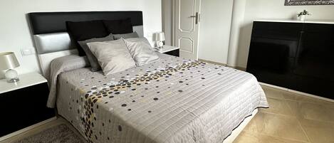 Ein Schlafzimmer mit einem Bett, Nachttischen, einem Spiegel und einem Bild an der Wand.