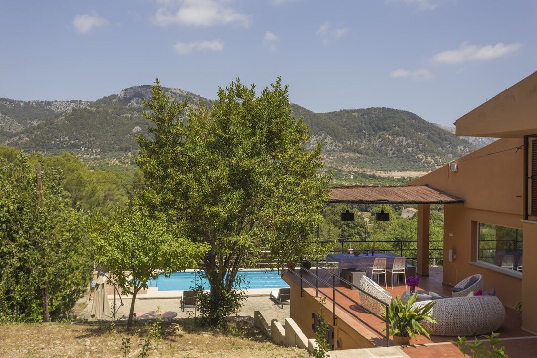 En villa med pool, utomhusmöbler och utsikt över bergen.