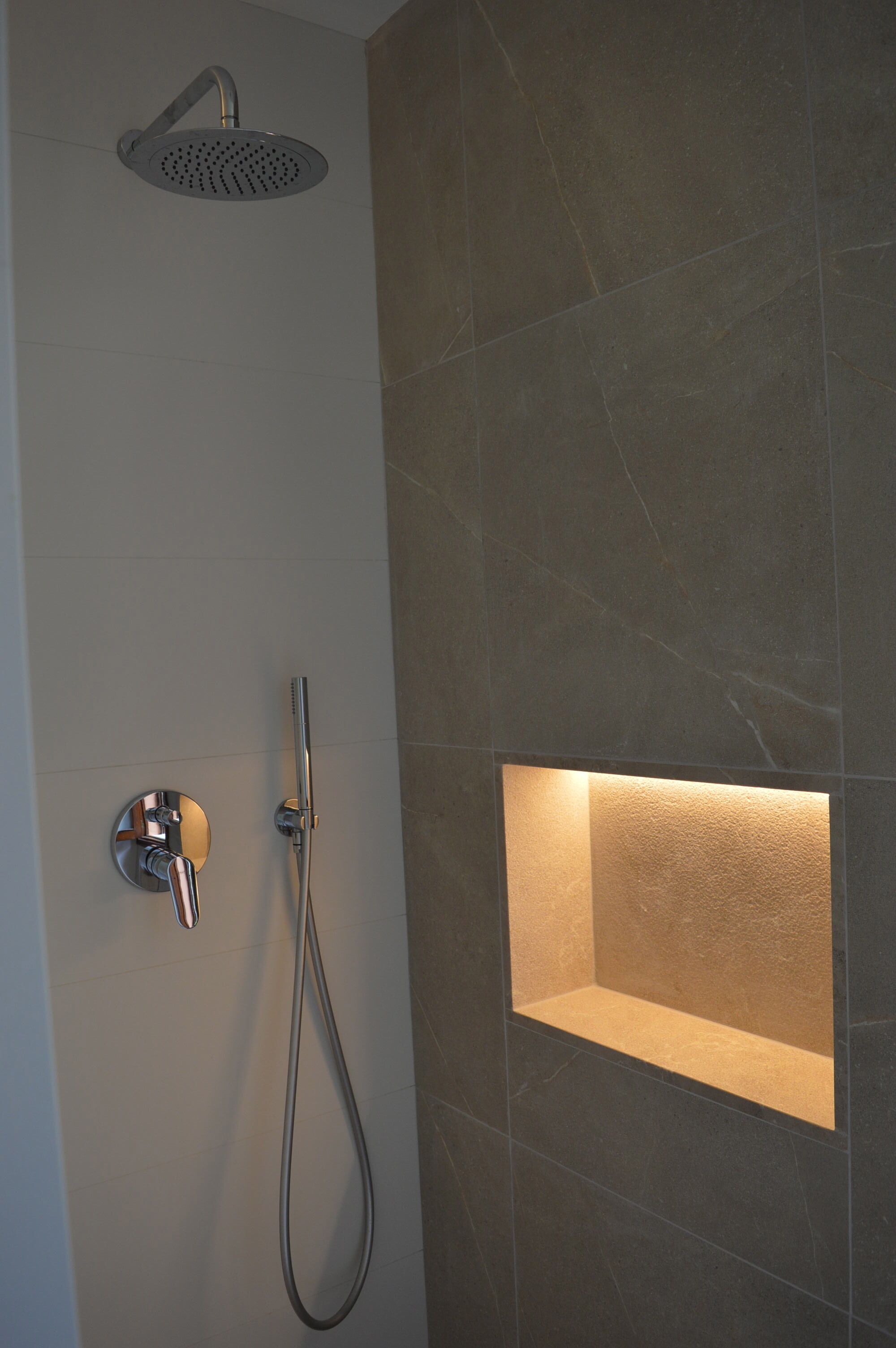 A modern bathroom with a showerhead, handheld shower, and a built-in bathtub.